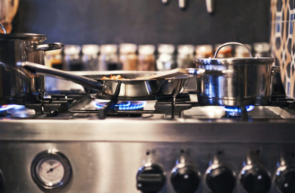 A propane stove cooking food in a frying pan and pot